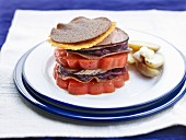 A stack of sliced beefsteak tomatoes, galette, andouille sausage from Guéméné and red cabbage
