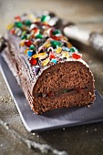 Chocolate log cake coated with candied fruit