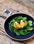 Breaded soft-boiled egg with raw baby spinach