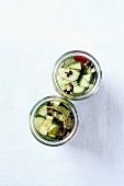 Pickled cucumbers with chilies and spices in preserving jars
