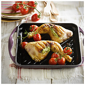 Grilling chicken thighs with bunches of cherry tomatoes and herb sauce