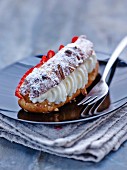 Eclairs with flaked almonds, passion fruit cream, jam, whipped cream and strawberries