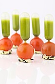 Pipettes with basil cream stuck in cherry tomatoes