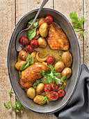 Spicy chicken breasts with potatoes and vine tomatoes in a roasting pan