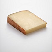 Ein Stück Comté-Käse vor weißem Hintergrund