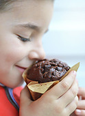 Kind riecht an einem Schokoladenmuffin
