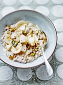 Porridge mit Hirseflocken, Buchweizen, Reisdrink, Birne, Banane und gehackten Pistazien