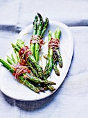 Bundles of green asparagus with anchovies, smoked bacon and thyme