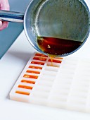 Pouring the hot syrup into small rectangular silicone molds