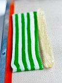 Bergamotten-Berlingots herstellen: Die durchsichte Zuckerpastenwurst neben die 8 Streifen gefärbte Zuckerpaste legen