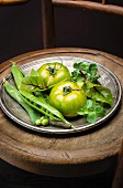 Dish of green tomatoes, peas, basil, lettuce and beetroot leaves