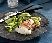 Cod fillet wrapped in smoked bacon with rosemary, thin strips of courgettes and lemon