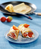 Rolled crêpe garnished with cream and strawberries