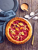 Peach-raspberry pie with plant-patterned pastry decoration