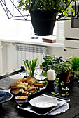 Table set with bread decorated with various plant pots and candlesticks