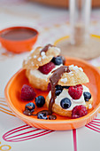 Profiteroles garnished with whipped cream,summer berry and chocolate sauce