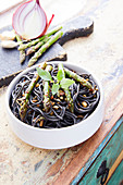 Squid ink spaghetti with green asparagus and onions
