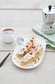 Roasted bananas with whipped cream, coffee toffee sauce and crushed hazelnuts