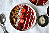 Strawberry and raspberry smoothie bowl with grated coconut and granola