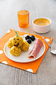 Rice balls with turmeric, paprika and saffron, pumpkin style, black olives and raw ham, pumpkin cream with spices