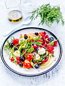 Salat mit Avocado, Kirschtomaten, Waldfrüchten und Mozzarellabällchen mit nativem Olivenöl extra