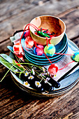 Gestapeltes Geschirr mit Pompongirlande und Gänseblümchen