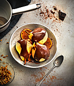 Pochierte Birnen mit Schokoladensauce, gebratenen Orangen und gerösteten Pinienkernen