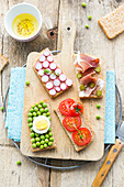 Assortment of multicolored fresh vegetable and raw ham toasts