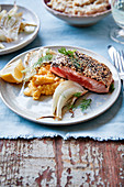 Piece of half-cooked salmon with black and golden sesame seeds,pumpkin mash,fennel and dill
