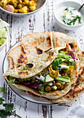 Flat breads with roasted cauliflower chickpeas spices and vegetables, yoghurt sauce