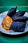 Fried squid ink raviolis,cream cheese and paprika quenelles