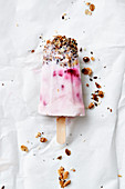 Homemade raspberry yoghurt ice cream on a stick with crunchy muesli