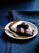 Ein Stück Joghurttarte mit Traubenkompott, schwarzem Pfeffer und Ingwerkruste