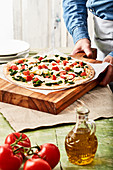 Ungebackene Pizza mit Spinat und Mozzarella auf Holzbrett