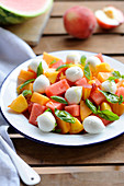 Watermelon, melon, peach and mozzarella ball salad with basil