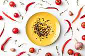 Peppercorns on a plate surrounded by chillies and tomatoes