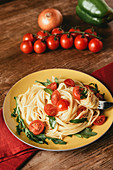 delicious italian pasta with tomatoes and arugula in plate