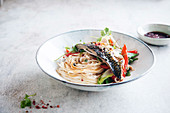 Mackerel cooked in foil with pink pepper on Asian noodles