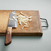 Thinly sliced onions with a knife on a wooden board