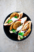 Pita breads garnished with falafels, tabbouleh and mint