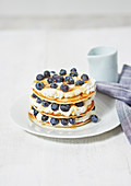 Pancakes stacked with cream filling and blueberries