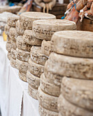 Cheese wheels stacked on a market stall