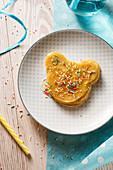 Pancakes in the shape of a bear with agave syrup and coloured sugar sprinkles