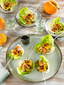 Garnelenspießchen mit Pfirsich serviert in Salatblättern