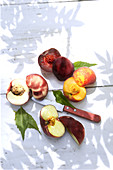 Different kinds of peaches on a sunny wooden background