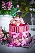 Chocolate cake decorated with ruby chocolate bars, raspberries and rose petals