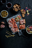 Vorspeisenplatte mit Schinken, Salami, Oliven, Brot- und Gemüsechips