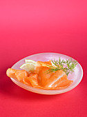 Smoked salmon on a plate in front of a pink background