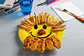 Kindergericht mit Pommes, Nuggets und Ketchup auf Teller mit Smiley