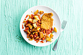 Breaded poultry with cooked tomatoes and fried potatoes